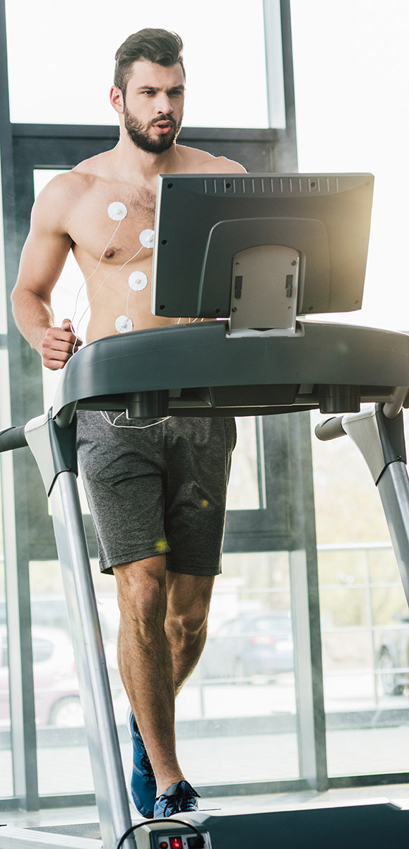 handsome sportsman with electrodes running on treadmill during e